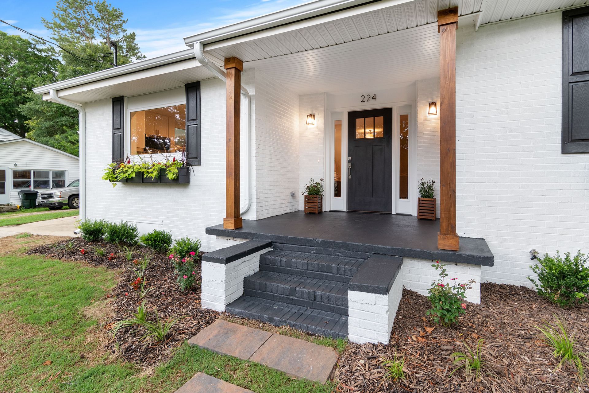 Front view of a charming white brick suburban house with black accents.
